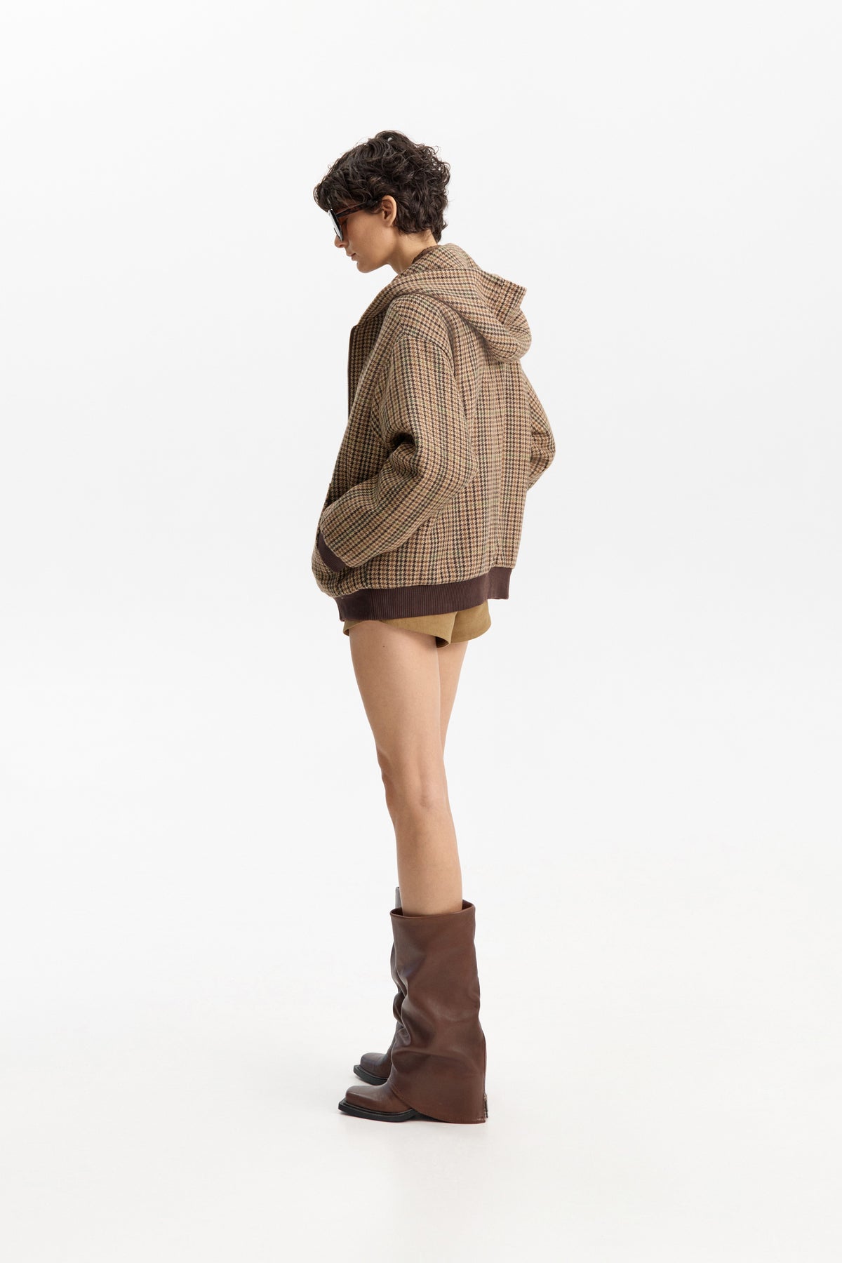 The ELEH - FIRENZE HOODED BOMBER by ELEH is a brown jacket with a classic check pattern, zip-up front, long sleeves, and ribbed cuffs and hem, displayed against a plain white background.