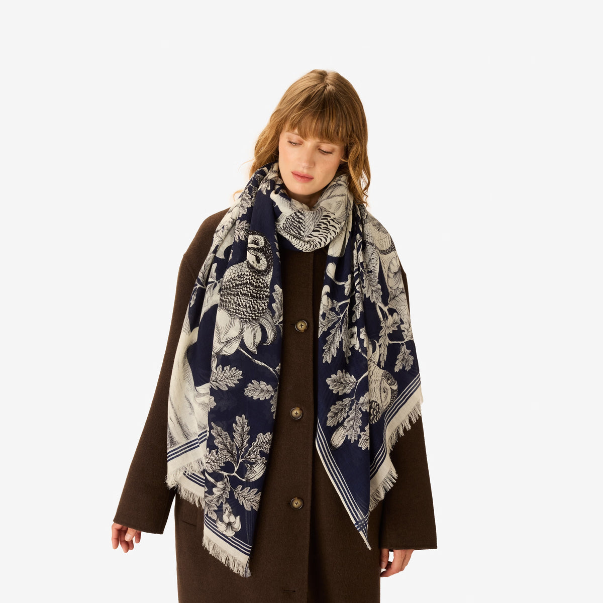 The INOUI EDITIONS - ARCHIMEDE WOOL SCARF IN NAVY by INOUI is crafted in India and features a detailed tree adorned with numerous birds and flowers on its branches, set against a white background.
