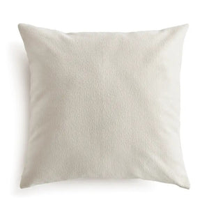 The NAPA HOME AND GARDEN - COOPER SQUARE OUTDOOR PILLOW 24" is a plain, light beige cushion with soft, textured recycled fabric. Plush and comfortable, it's ideal for sofas or beds. Shown against a white background.