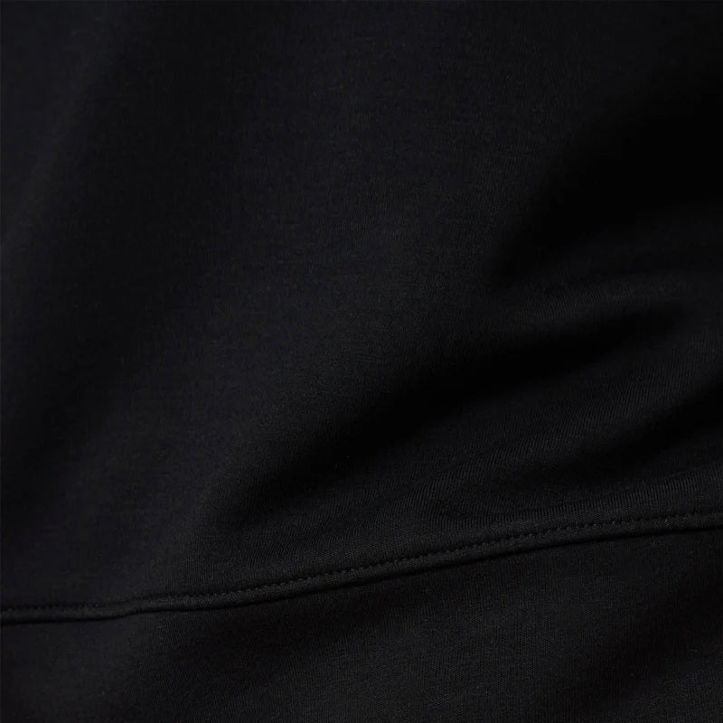 A woman wears a SOFTIES - DREAMTECH BOAT NECK WITH PINTUCK PANT SET in olive green, featuring a long-sleeve boat neck top and matching wide-leg pintuck pants.