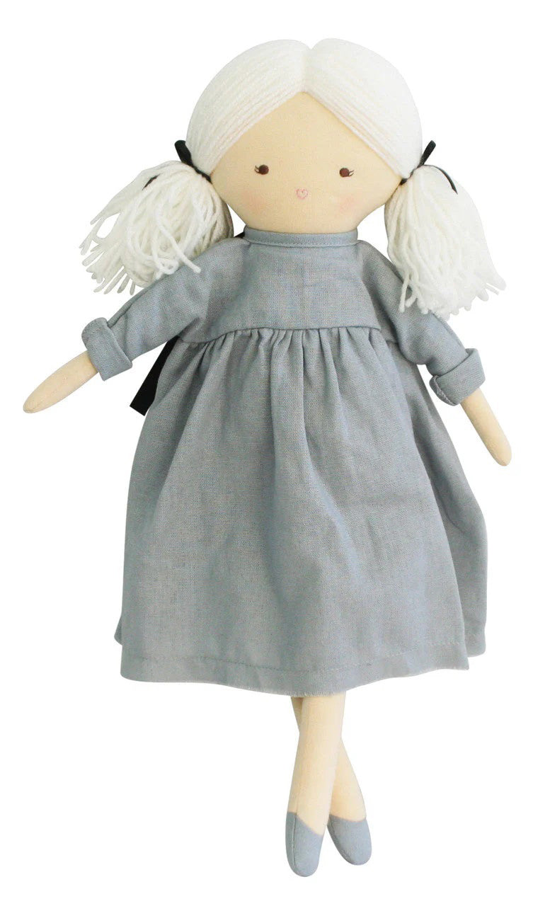 The ALIMROSE - MATILDA DOLL IN DOVE GREY from ALIMROSE is an adorable 45cm doll featuring white yarn hair tied in two pigtails with black ribbons. This charming doll is dressed in a light gray linen dress with a gathered waist and sleeves, paired with matching shoes. It has a simple, stitched face adorned with a small smile and red heart-shaped lips.