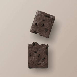 A STARS+HONEY - MINT COOKIES & CREAM Collagen Protein Bar, with its wrapper, displays mint chocolate ice cream and cookie pieces bursting out for a dynamic effect against a beige background.