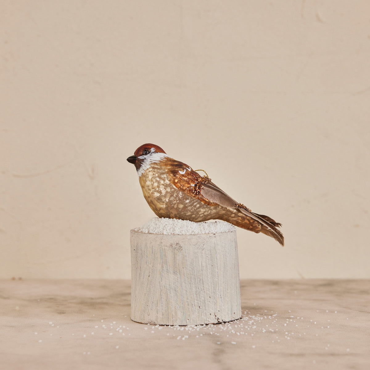 The CREATIVE COOP MERCURY GLASS BIRD ORNAMENT features brown and gray coloring, glitter bead accents, and a gold hanging string, shown isolated on a white background.