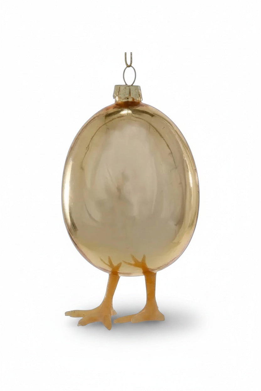 A WHAT CAME FIRST? ORNAMENT by Cody Foster, featuring a 4.75-inch gold, egg-shaped ornament with two yellow bird feet at the base.