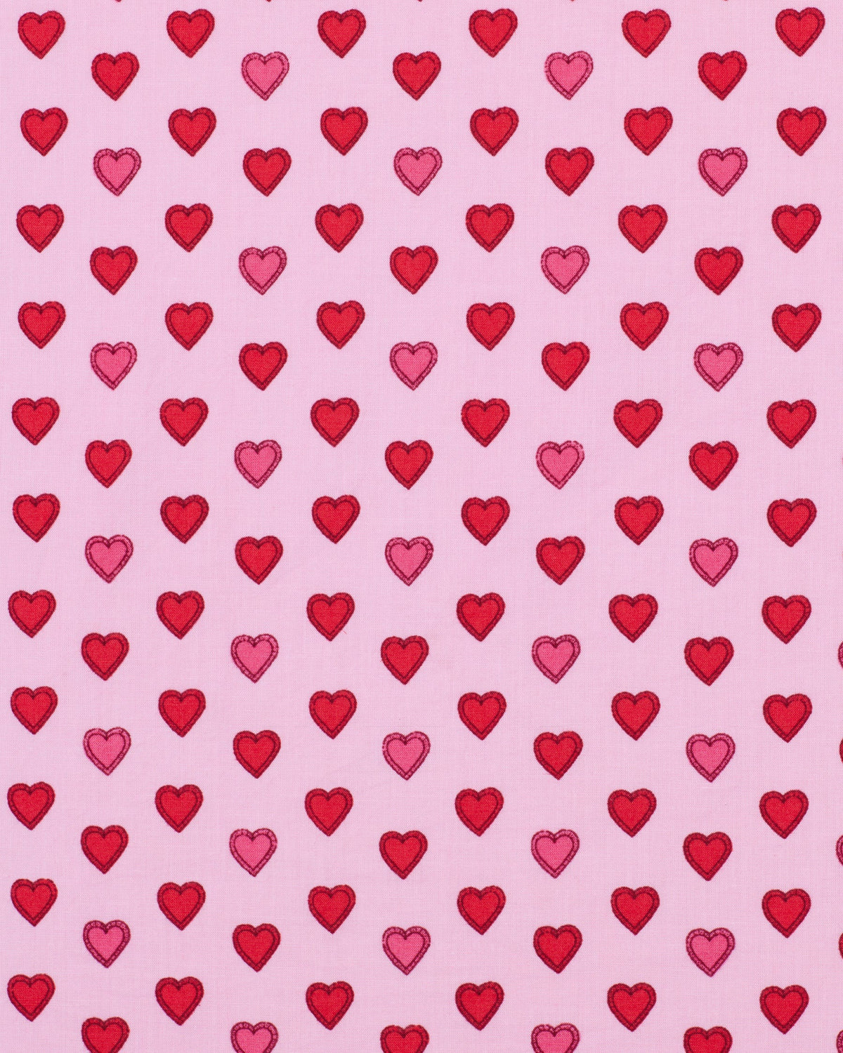 A person wearing the PRINTFRESH - MINI CANDY HEARTS PAJAMA SHORT SET by PRINTFRESH, featuring pink fabric with red heart patterns, stands with one hand in their shorts pocket. The image highlights the details of the pajama set and does not show the person's face.