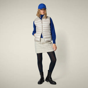 The SAVE THE DUCK - LYNN PUFFER VEST IN BLUE FOG is a light blue, sleeveless women’s vest with horizontal quilting and a high collar, shown zipped up and laid flat. Lightweight nylon ensures comfort and style. Brand: SAVE THE DUCK.