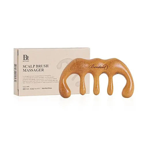 A natural sandalwood SCALP MASSAGER COMB by KOSMIC KBEAUTY SKINCARE with four rounded prongs sits before its beige box labeled "Scalp Brush Massager." The smooth, ergonomic design offers gentle acupressure for the scalp.