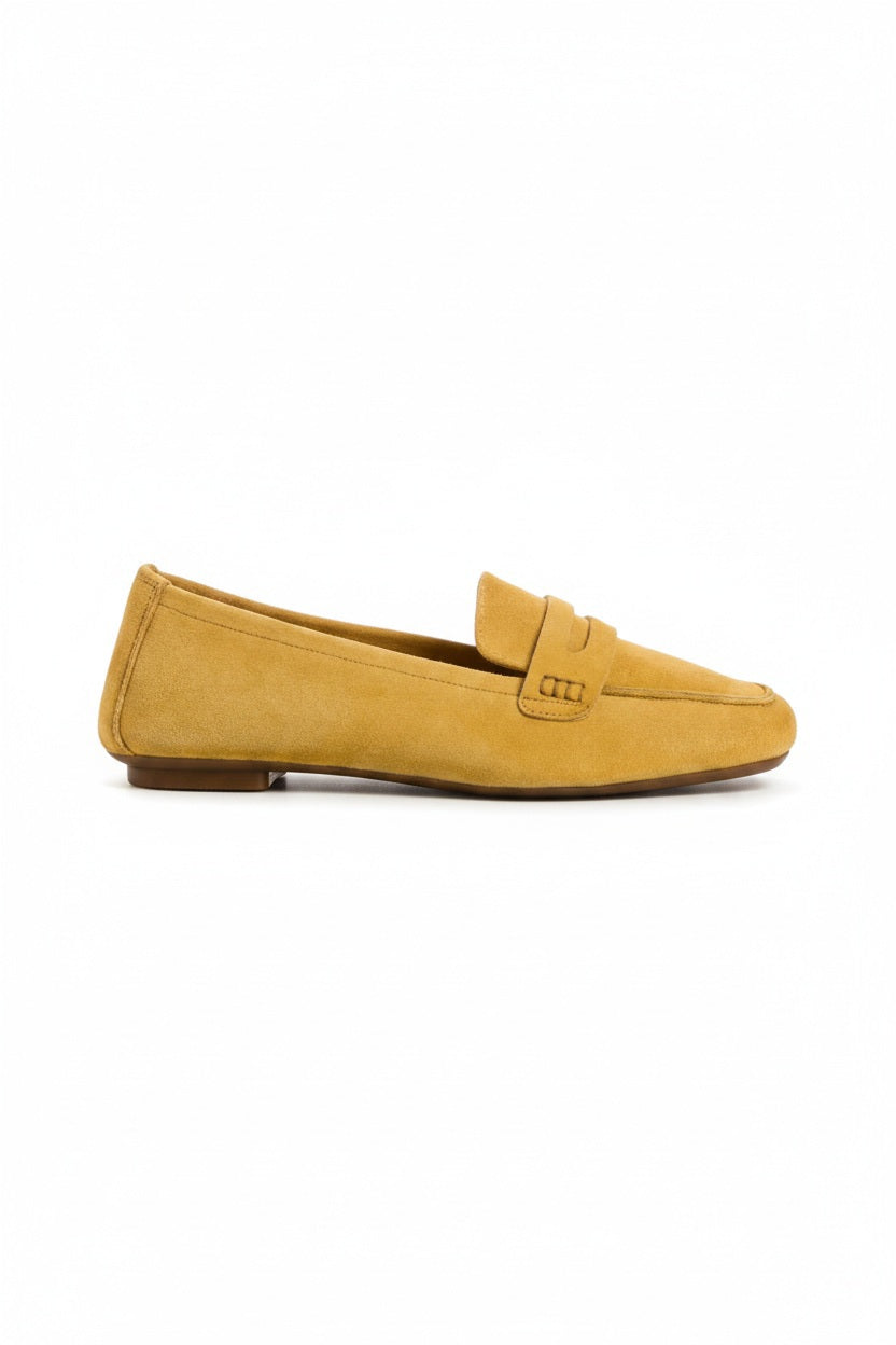 The REQINS - HEMA Suede Loafer in Ochre, expertly crafted by REQINS, features a low heel and a decorative front strap, shown against a plain light background.