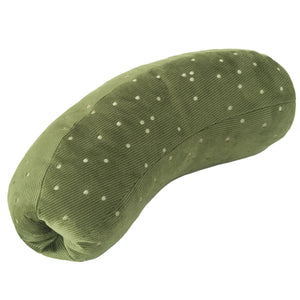 A black dog lies on a white textured blanket, holding the LAMBWOLF COLLECTIVE - GIANT PICKLE DOG TOY—a green, polka-dotted toy—under one paw, its tongue sticking out.