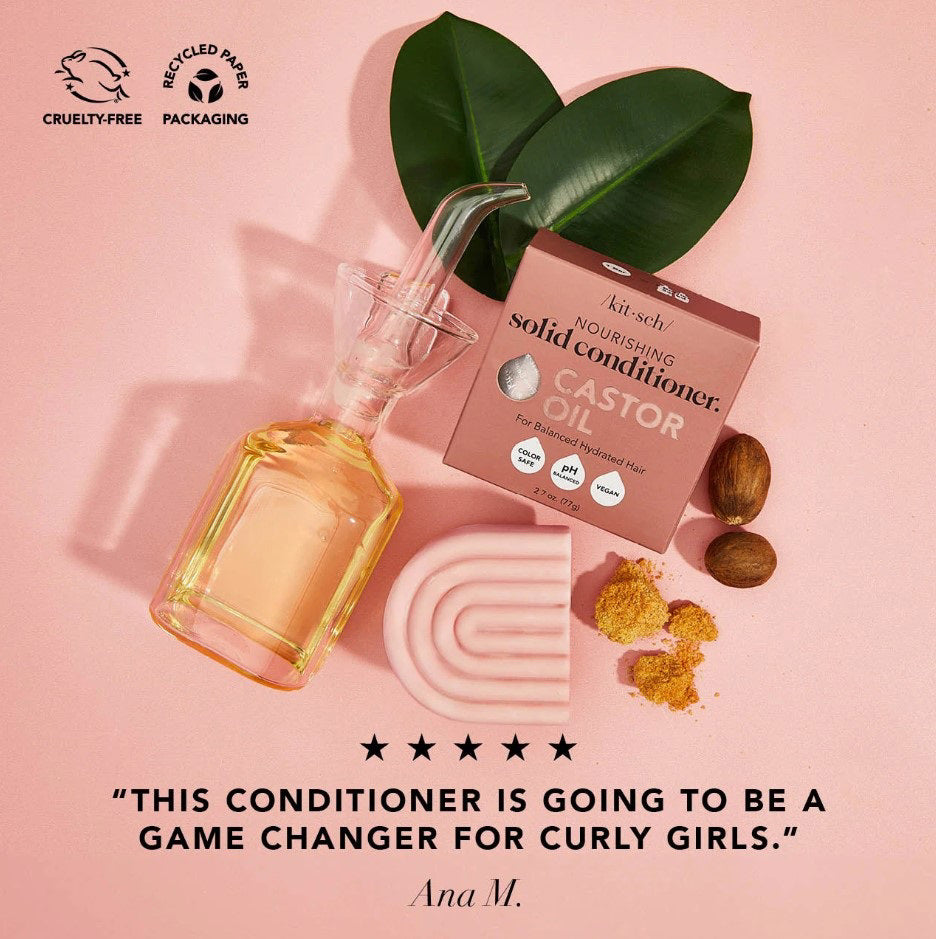 A pink KITSCH - CASTOR OIL NOURISHING CONDITIONER BAR and its box are shown with castor beans. The box notes it's color safe, pH balanced, vegan, and designed to nourish dry hair while controlling frizz.
