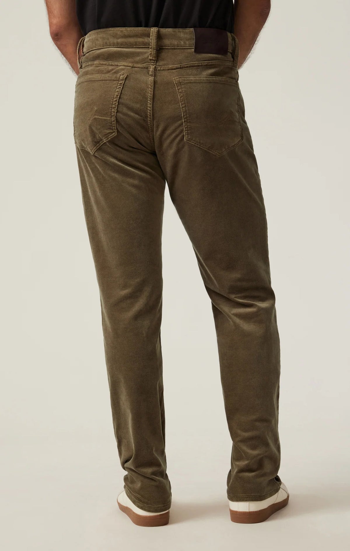 Man wearing 34 HERITAGE - COURAGE STRAIGHT LEG CORDUROY PANTS IN TOBACCO and white sneakers.