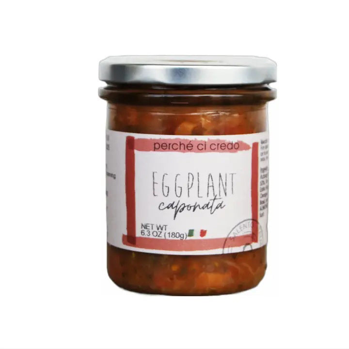 A 6.3-ounce (180-gram) glass jar of PERCHE CI CREDO - EGGPLANT CAPONATA by ZIA PIA IMPORTS, featuring a metal lid and a label decorated with the colors of the Italian flag, contains a chunky, dark orange vegetable mixture that provides an authentic, ready-to-eat taste of classic Sicilian cuisine.