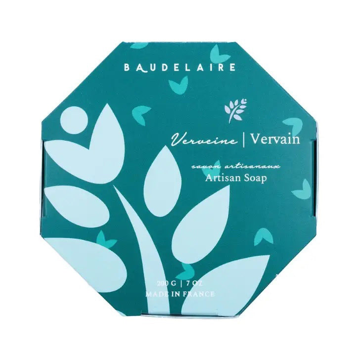 A hexagonal teal-colored box labeled &quot;BAUDELAIRE&quot; at the top. The text reads &quot;Verveine/Vervain savon artisanal - Artisan Soap.&quot; Infused with shea butter and boasting a vervain scent, the design includes light blue abstract shapes resembling flowers and leaves. The bottom text indicates 200 g / 7 oz, Made in France. This product, known as the BAUDELAIRE - VERVAIN 7OZ BOXED BATH BAR, is offered by the brand BAUDELAIRE.

