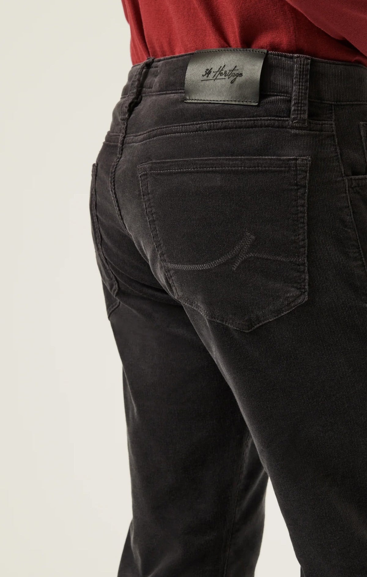 34 HERITAGE - CHARISMA RELAXED STRAIGHT LEG CORDUROY PANTS IN CHARCOAL worn with a red long-sleeve shirt and black leather boots.