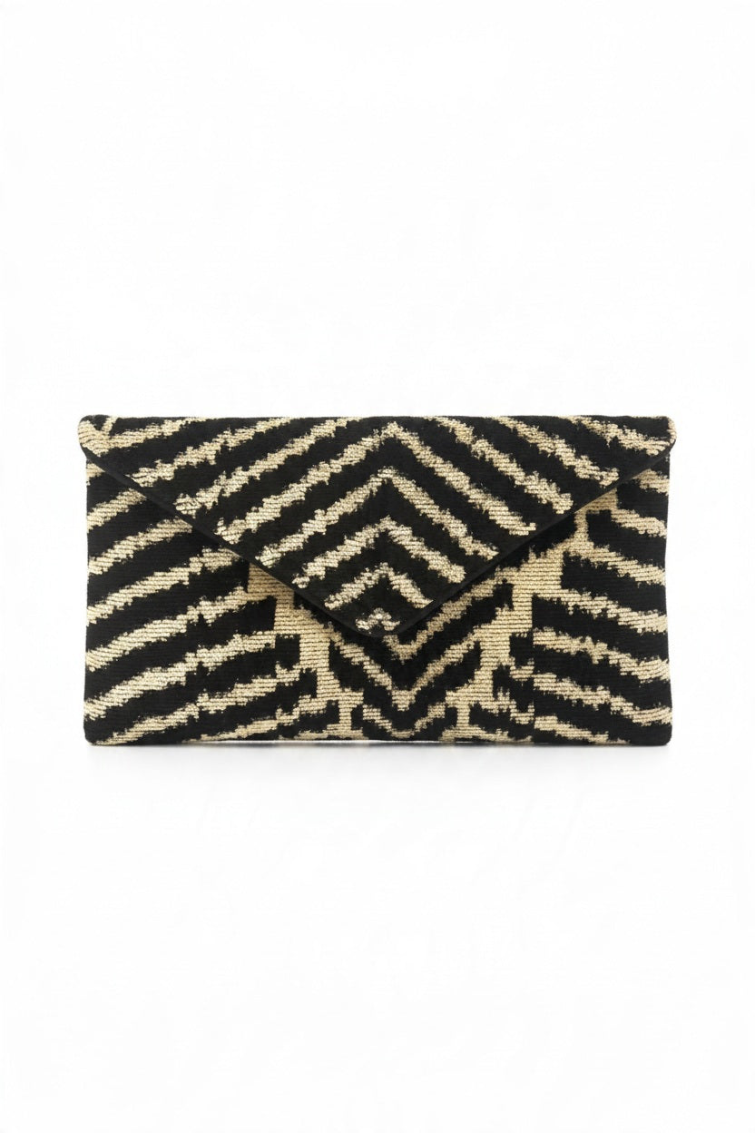 Handcrafted, envelope-style BALDIZ - DESERT ZEBRA LILY CLUTCH in a black and tan geometric striped pattern.
