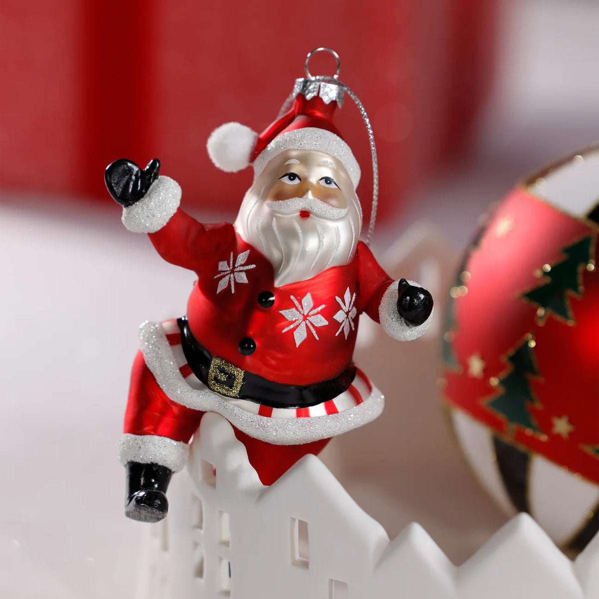 The ZODAX DANCING SANTA ORNAMENT features Santa in a red suit with white trim, snowflake patterns, black boots, and a black belt, hanging by a silver string against a white background—perfect for holiday cheer.