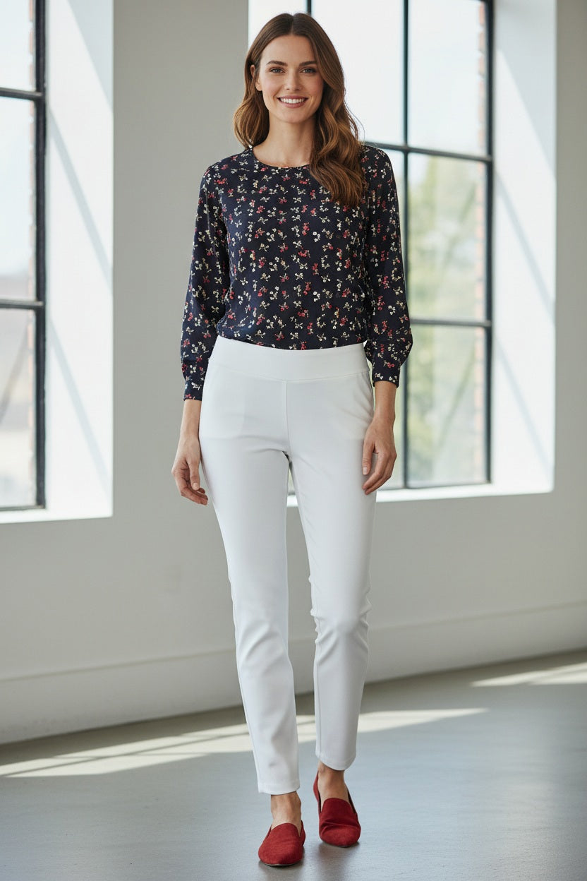 Wearing the KRAZY LARRY, INC PULL ON STRAIGHT LEG MICROFIBER PANT in white, paired with a dark patterned top and red shoes, a person poses against a white background. The image features only the lower half of their body, highlighting this chic office-ready style.