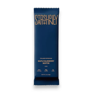 A blue wrapper labeled “STARS+HONEY - MAPLE BLUEBERRY MUFFIN”—a tasty collagen protein bar blending maple and blueberry flavors from the brand STARS+HONEY—rests on a beige surface, with nutritional information visible.