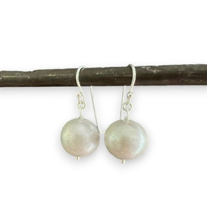 ANN LIGHTFOOT FRESHWATER PEARL DROP EARRINGS feature a single round white freshwater pearl on sterling silver earwires, shown hanging from a dark rod against a white background.