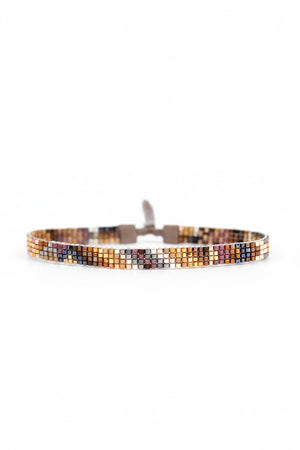 The JULIE ROFMAN - ORO BRACELET by JULIE ROFMAN JEWELRY features a handwoven design with small, vibrant square beads in shades of orange, yellow, pink, and black. This stylish bracelet is finished with a loop closure on a white background.