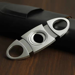The AMERICAN LEATHER GOODS Leather Cigar Case with Wood-Lined Humidor and Cutter in Black rests on a wooden surface, with another travel humidor case in brown visible in the background.