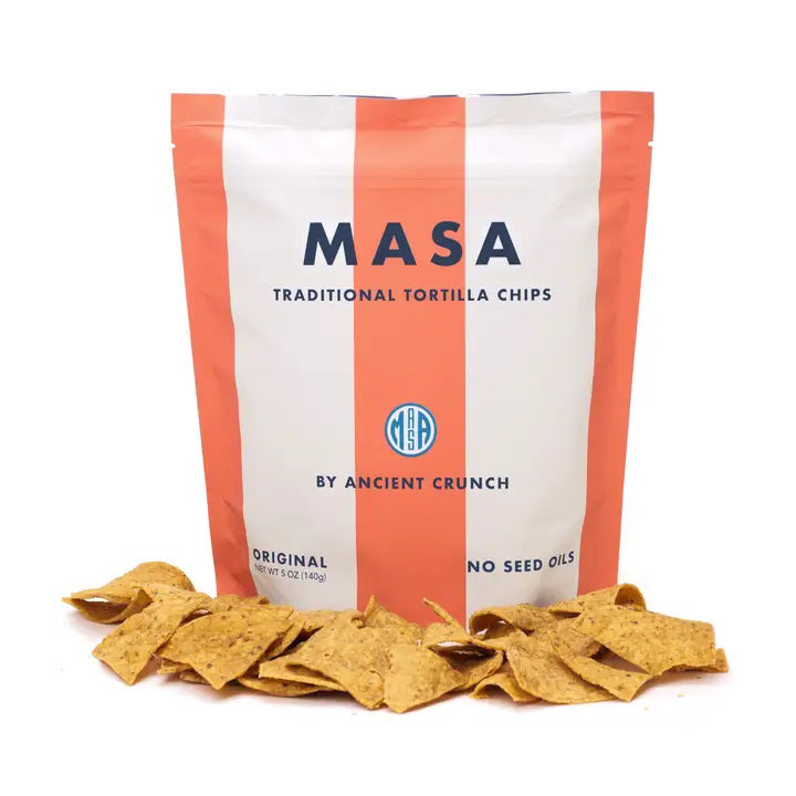 A bag of ANCIENT CRUNCH - TRADITIONAL TORTILLA CHIPS by ANCIENT CRUNCH with red and white stripes stands upright, labeled &quot;Original&quot; and &quot;No Seed Oils,&quot; highlighting its seed oil-free recipe with crunchy chips scattered in front.