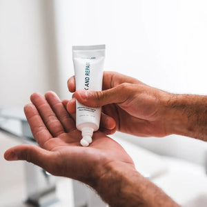 A white tube labeled "JAXON LANE - RELAX AND REPAIR ANTI AGING FACE MOISTURIZER" stands beside a matching black box. This fragrance-free men's moisturizer from JAXON LANE contains 2.03 fl. oz. (60 ml) of product.