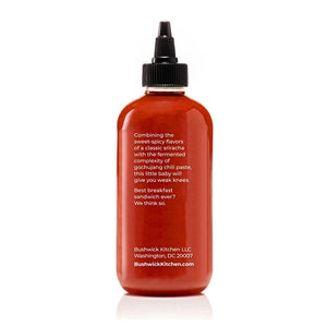A 10.5 oz (298g) bottle of BUSHWICK KITCHEN - 'WEAK KNEES' GOCHUJANG SRIRACHA hot sauce features a striking red design with a black cap and white text, proudly made in Brooklyn, NY, USA. This unique blend includes fermented chile paste for an exceptional kick.
