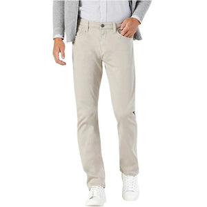A bearded man stands facing forward with one hand in his pocket, wearing a light gray cardigan over a white button-up shirt, 34 HERITAGE - COURAGE STRAIGHT LEG PANTS IN DAWN TWILL (beige), and white sneakers against a plain white background.