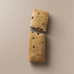 A brown STARS+HONEY - ESPRESSO VANILLA CINNAMON collagen protein bar wrapper labeled with its name and featuring nutrition details—10g collagen, 15g protein, and 2g sugar—lies on a matching brown surface, evoking classic cappuccino and espresso flavors.