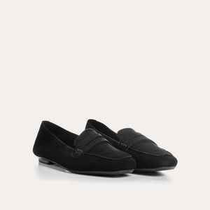 The REQINS HEMA Suede Loafer in Noir features a classic black silhouette, low heel, leather insole, and decorative front strap, shown against a plain light background.