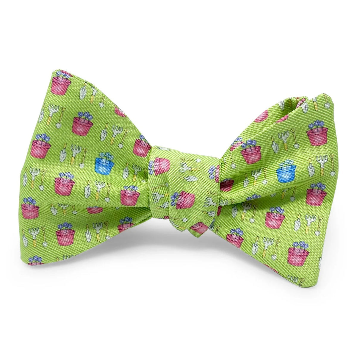 Introducing the BIRD DOG BAY PETER-BLAIR Garden Silk Bow Tie in Green, featuring a charming print of small pink and blue flower pots and white gardening tools. Handmade in North Carolina, this bow tie offers adjustable neck sizing for a perfect fit.