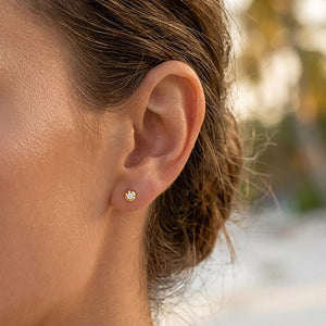 The ELLA STEIN - ALA STUD EARRINGS by ELLA STEIN are a pair of small gold stud earrings, each featuring a single round natural diamond set in a four-prong gold plated setting, displayed on a white background.
