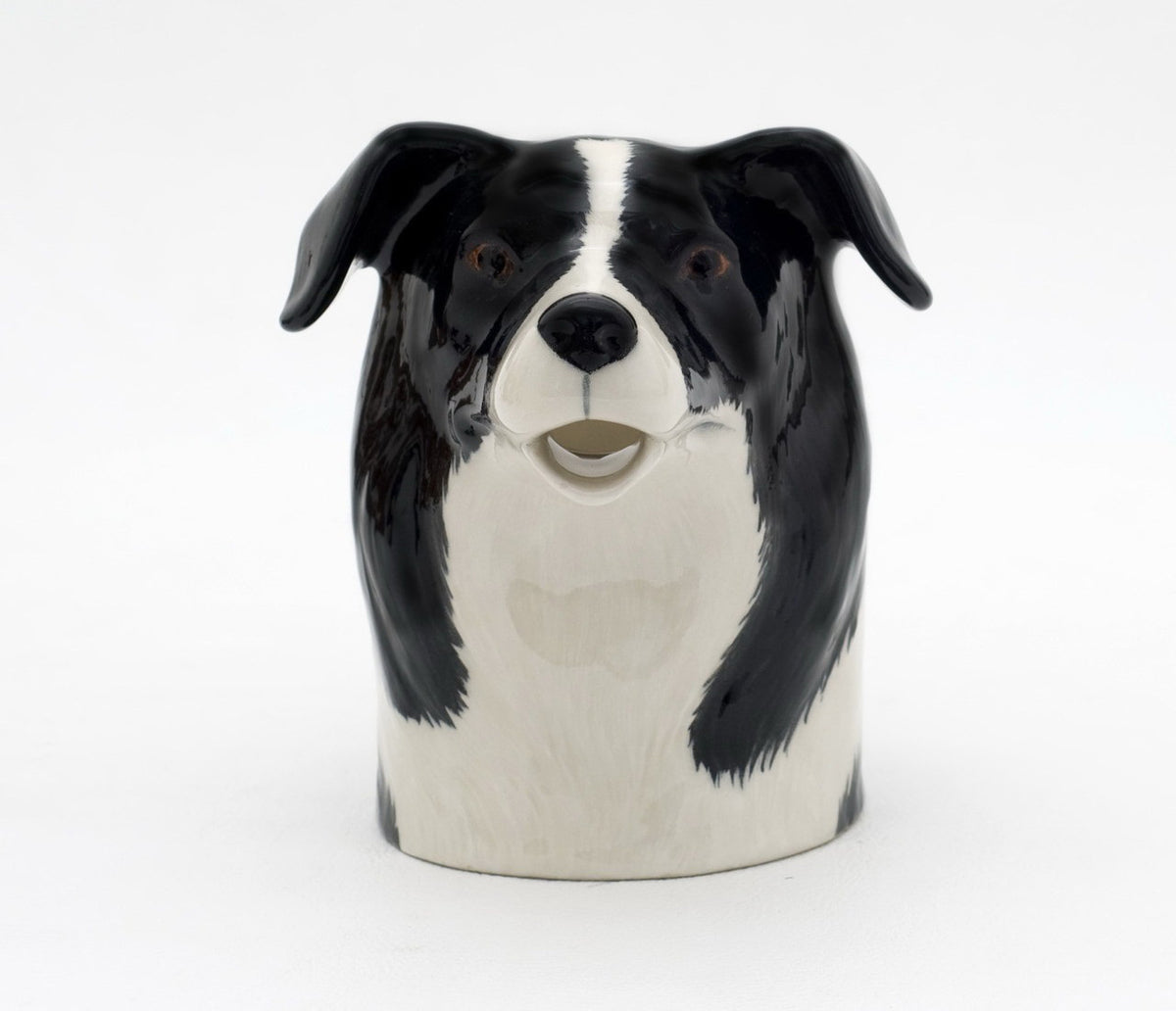 The QUAIL DESIGNS QUAIL CERAMICS Border Collie Jug is a handpainted stoneware jug shaped like a black and white dog, with the spout as the dog&#39;s open mouth, shown on a plain white background.