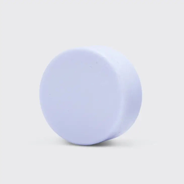 A KITSCH Purple Toning Solid Conditioner Bar sits on its packaging, which states it's formulated with Biotin for blonde and highlighted hair, neutralizing brassiness. The labels affirm it's color safe, pH balanced, and vegan.