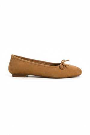 The REQINS - HARMONY SUEDE BALLERINA FLATS IN CAMEL feature a tan suede finish, a small bow on the toe, a low heel, and an elegant, simple design against a plain light background.