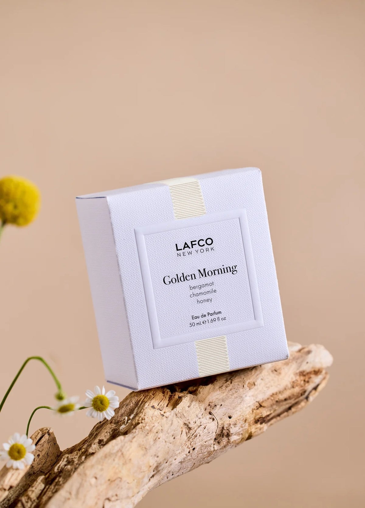 A transparent perfume bottle labeled “LAFCO - FINE FRAGRANCE, GOLDEN MORNING 50ML” by LAFCO features a round, marble-textured cream cap and is displayed against a plain white background. This floral scent is crafted as a vegan and cruelty-free fine fragrance, designed to deliver a sophisticated and conscious olfactory experience.