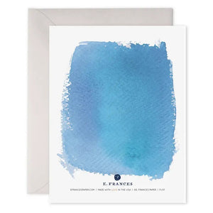 The E. FRANCES - HUG CARD by E. FRANCES PAPER features a blue watercolor design with "hug" embossed in silver on the front and comes with a light gray envelope. This comfort card is ideal for sending warm thoughts and support.