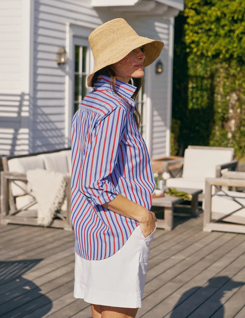 A woman smiles in sunlight while wearing the FRANK &amp; EILEEN EILEEN Relaxed Button Up Shirt in Superluxe Cotton Stripe, accessorized with gold rings and a delicate necklace.