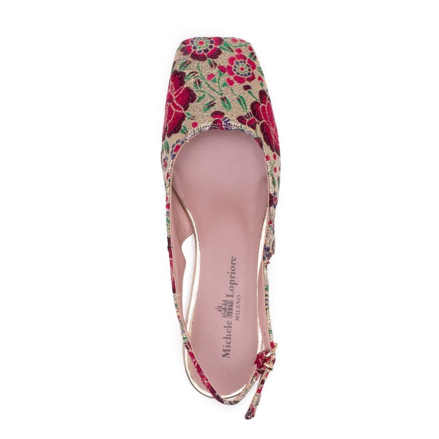 Side view of the MICHELE LOPRIORE - SQUARED SLINGBACK, a single slingback flat shoe with a colorful floral pattern featuring shades of pink, red, green, and blue. This Italian-made shoe has a closed pointed toe, an adjustable gold buckle on the ankle strap, and a small gold heel. It boasts a genuine leather sole for added comfort and durability courtesy of the brand MICHELE LOPRIORE.