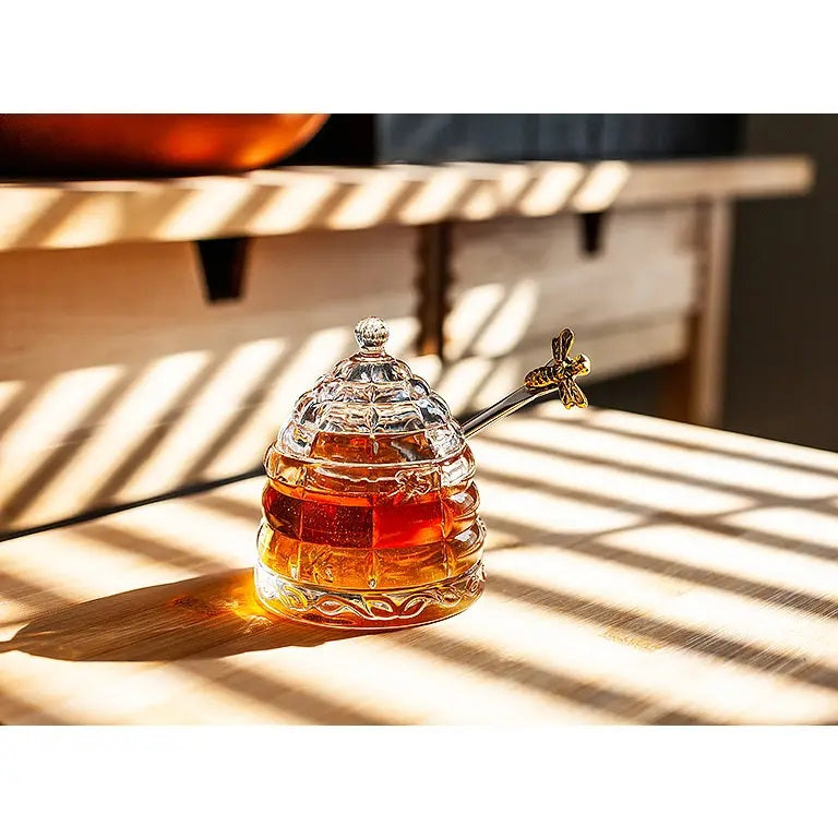 ABBOTT BEEHIVE HONEY POT WITH LID, a clear glass beehive-shaped pot with a matching lid and a silver honey dipper.