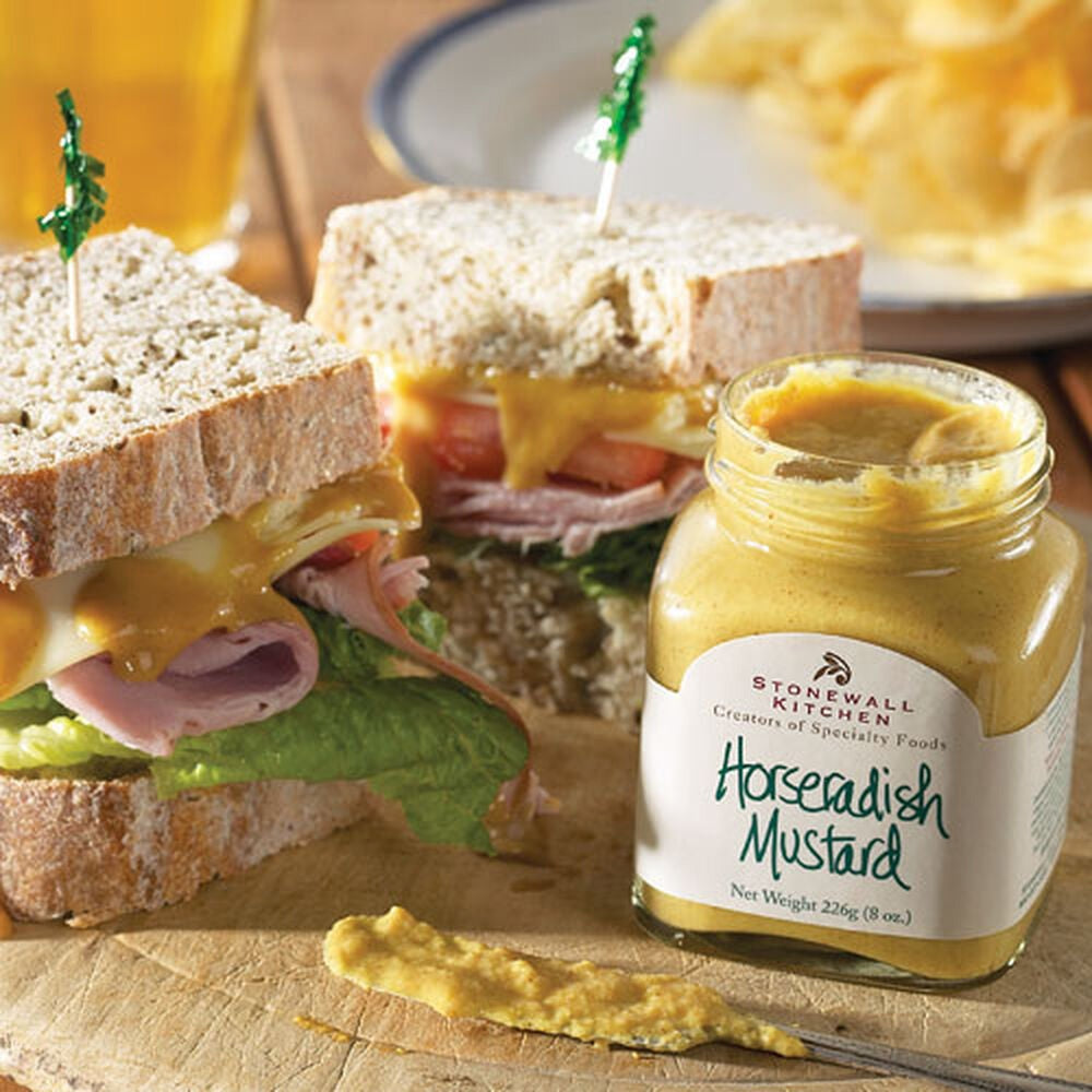 An 8 oz jar of STONEWALL KITCHEN - HORSERADISH MUSTARD, featuring a green lid and a cream label that highlights its gluten free and non-GMO qualities. This pale yellow mustard from STONEWALL KITCHEN is ideal for giving your roast beef sandwich a bold, savory kick.