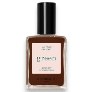 A hand adorned with MANUCURIST - GREEN™ Nail Polish in Chestnut by MANUCURIST INC rests on a wooden table beside a cup of coffee with heart-shaped latte art and a small pastry sprinkled with coarse sugar.
