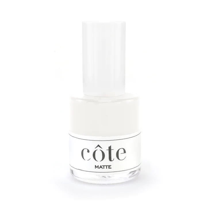 A clear bottle of Côte nail polish labeled "MATTE TOP COAT TREATMENT" is placed against a white background. The bottle, featuring a white cap and a white label with black text displaying the brand name "Côte," promises a velvety finish with its Matte Top Coat Treatment formula.