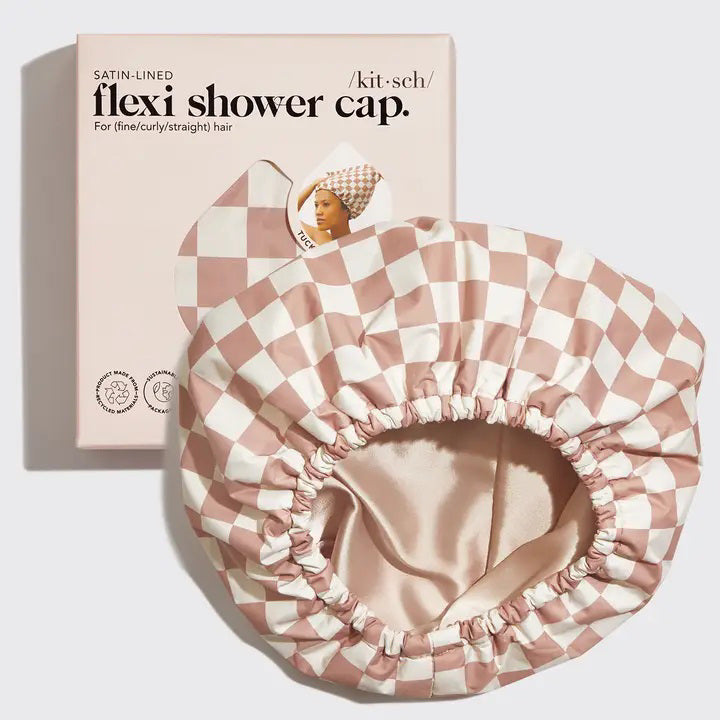 The KITSCH - SATIN LINED FLEXI SHOWER CAP, featuring a checkered pink and white design, is waterproof with satin lining and comes with adjustable closure for various hair types, as shown on its packaging.