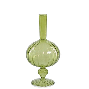 Five uniquely shaped green glass vases, including the striking ZODAX VENETIAN SPIRAL VASE IN GREEN ONION SHAPE (7.5”), are arranged on a reflective tray. Two of the vases display decorative branches with red berries, set against a soft, neutral-colored background.