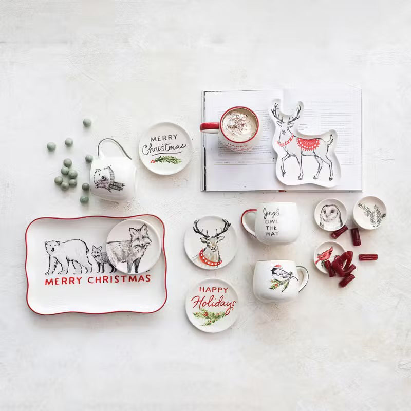 Six small, round Creative Coop stoneware dishes with hand-painted botanical animal illustrations of a hedgehog, owl, birds, or winter greenery.