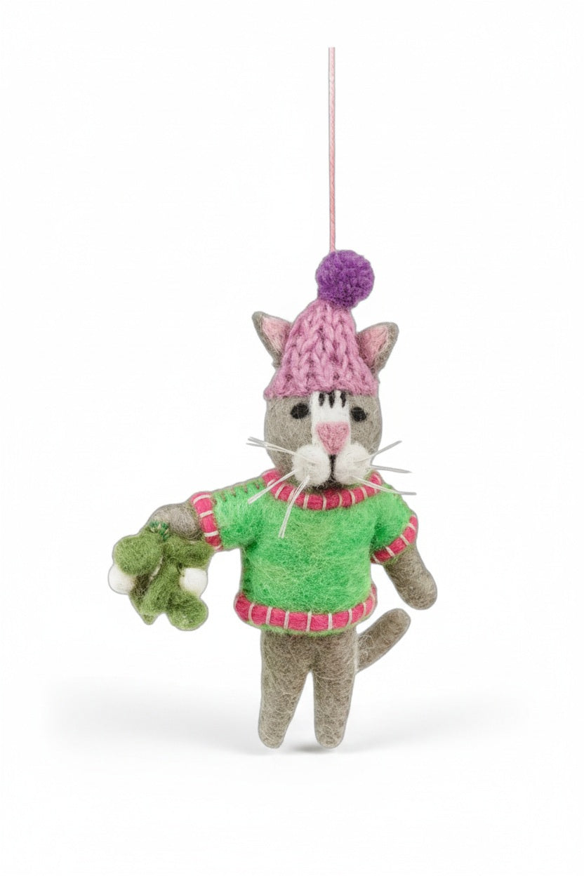 MISTLETOE MEOW ORNAMENT by FELT SO GOOD, a felt cat wearing a pink hat and a green sweater while holding a sprig of mistletoe.