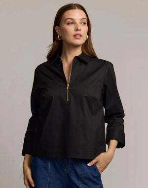 A woman with long brown hair is wearing the HINSON WU - ALESSA 3/4 SLEEVE SHIRT in black, crafted from stretch polished cotton, paired with blue jeans. She stands against a plain light background and looks at the camera with a neutral expression.