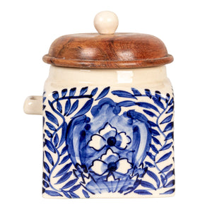 A close-up of the CREATIVE COOP HAND-PAINTED STONEWARE CANISTER WITH LID AND SPOON shows blue floral designs on cream stoneware and an acacia wood lid—an elegant farmhouse kitchen accent.